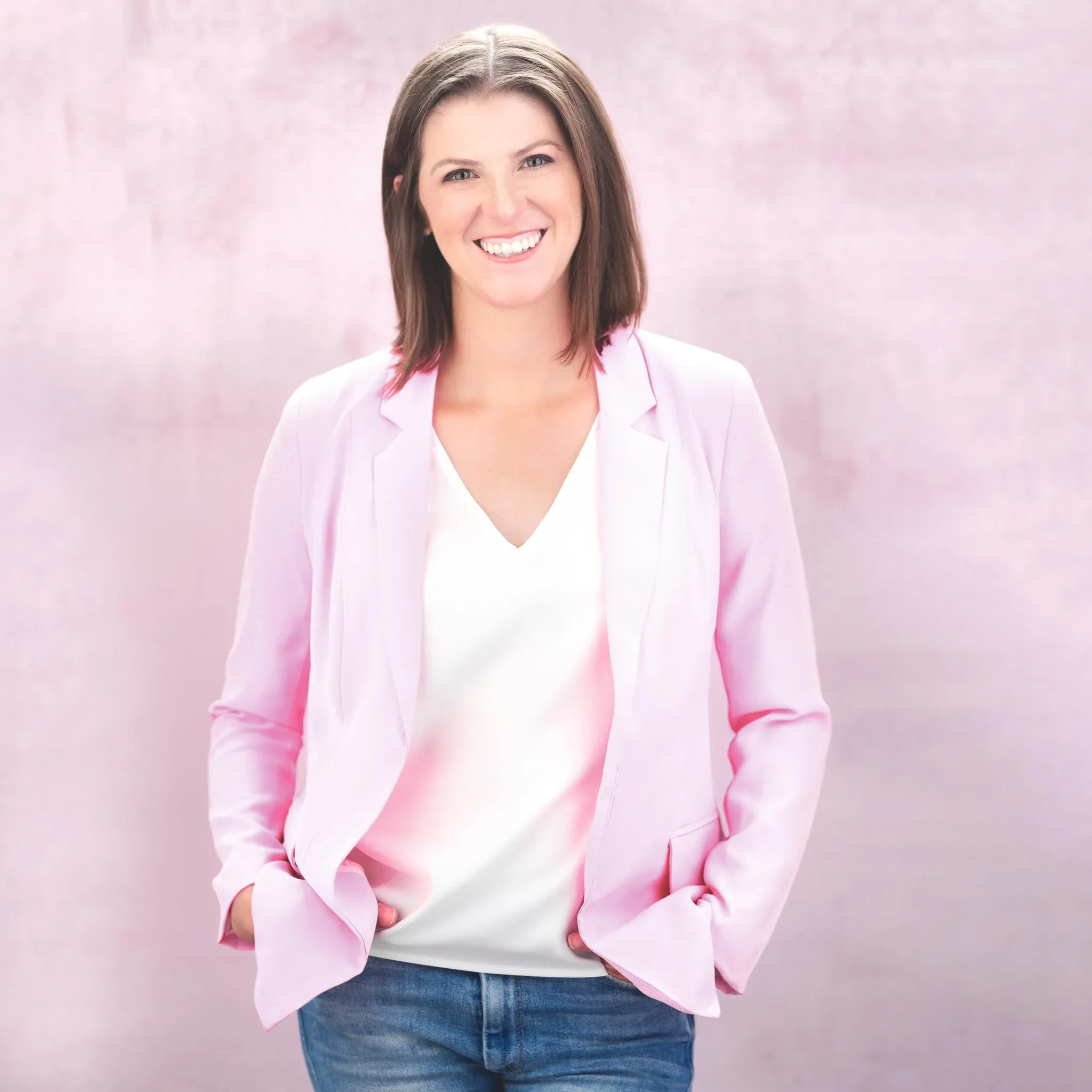 Elegant Professional Headshot for Personal Branding Professional headshot of a woman with a warm smile, wearing a stylish pink jacket against a light pink background.